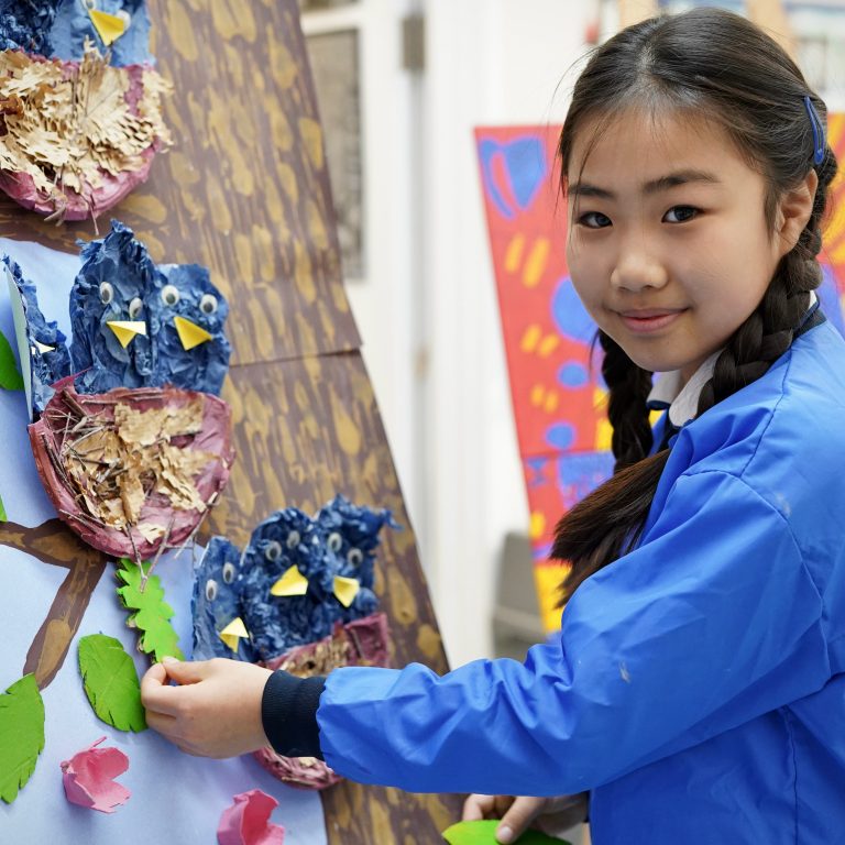 girl attaching artwork to a tree